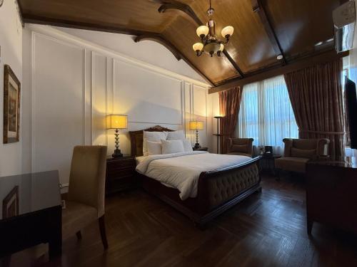 a bedroom with a bed and two chairs and a chandelier at S Chalet Islamabad in Islamabad