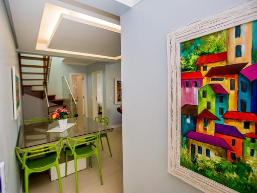 a dining room with a painting of houses on the wall at Residencial Villa Lobos in Torres