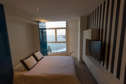 a bedroom with a bed with a television and a window at Virginia's Dream Panoramic Sea View Loft in Las Palmas de Gran Canaria