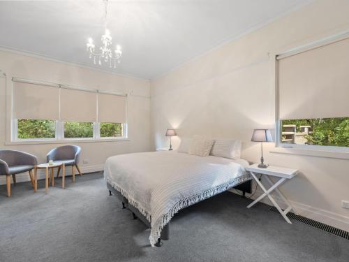 a white bedroom with a bed and two windows at The Gables in Marysville