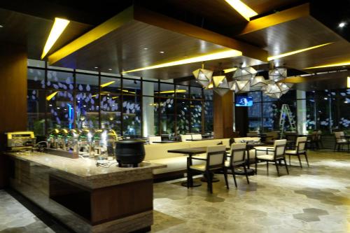 a restaurant with a bar with tables and chairs at Midtown Hotel Samarinda in Samarinda