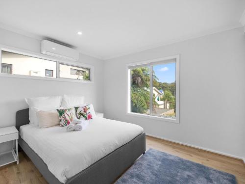 a white bedroom with a bed and a window at The Nest on Hull in Marysville