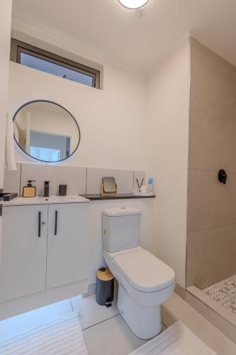 a white bathroom with a toilet and a mirror at The Stay Edit Windhoek in Windhoek