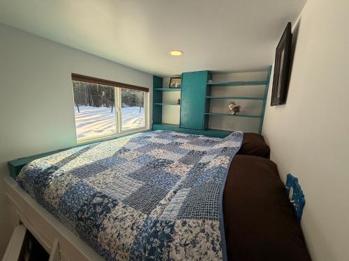 a bedroom with a bed with a quilt on it at Cozy Container in Soldotna