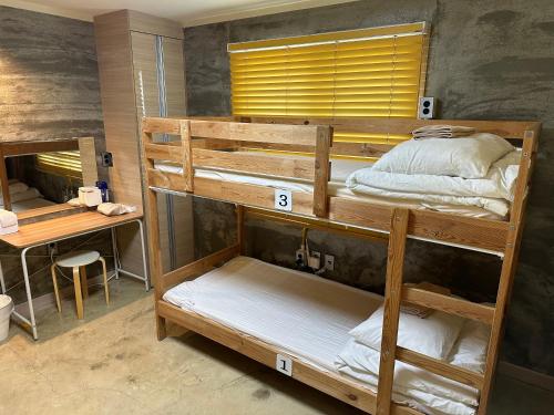 two bunk beds in a room with a desk at Osoha guest house in Samcheok