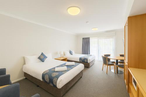a hotel room with two beds and a table at Esplanade Hotel Busselton in Busselton