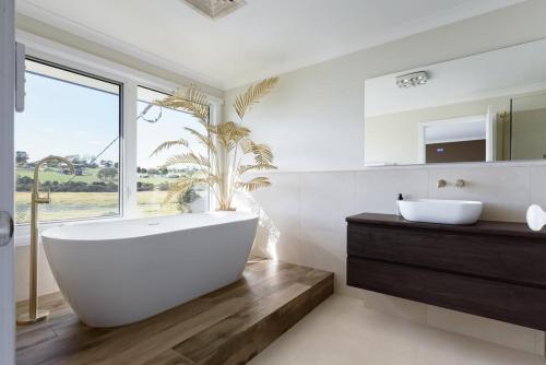 a bathroom with a large white tub and a window at Tamar River Hideaway in Legana
