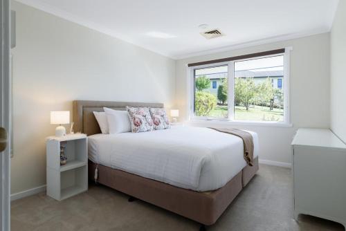 a white bedroom with a large bed and a window at Tamar River Hideaway in Legana