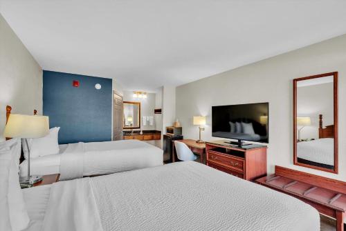 a hotel room with two beds and a flat screen tv at Baymont by Wyndham Warner Robins in Warner Robins