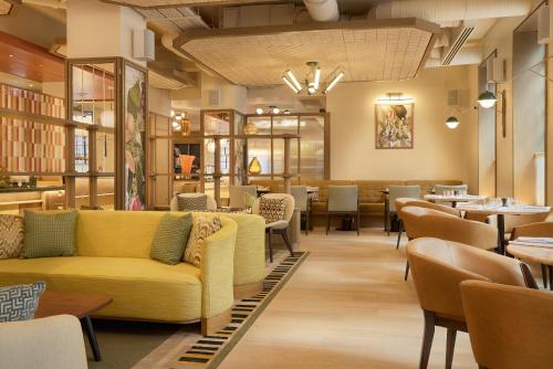 a restaurant with a yellow couch and tables and chairs at The Derby London City, Curio Collection By Hilton in London