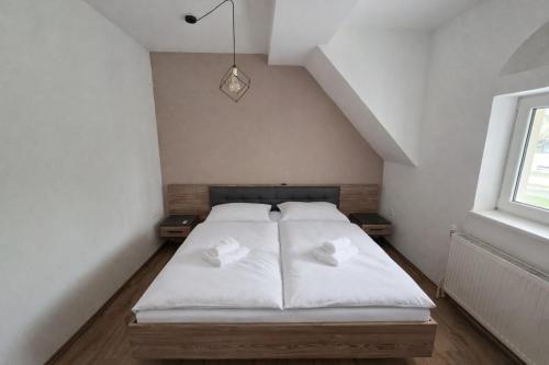a bedroom with a white bed with two pillows at Apartmány Bojnický Vínny Dom in Bojnice