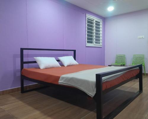 a bedroom with a bed with purple walls at Pani thuzhi in Salem