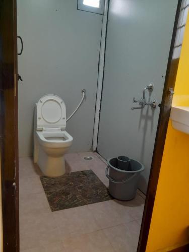 a small bathroom with a toilet and a bucket at Pani thuzhi in Salem