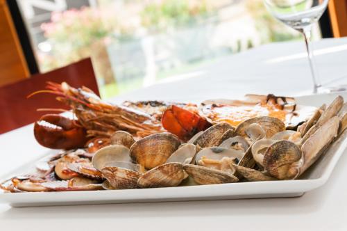 a plate of clams and shrimp on a table with a wine glass at Hotel Ruta de Europa in Vitoria-Gasteiz