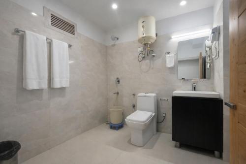 a white bathroom with a toilet and a sink at Hotel The Himalayan Riverside - Most Awarded Property of Manali 2025-26 in Manāli