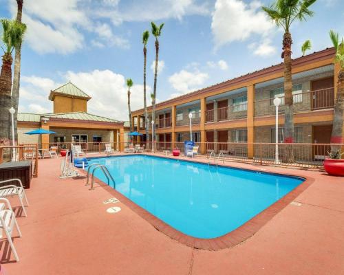 a swimming pool in front of a hotel with palm trees at Econo Lodge Inn & Suites Eagle Pass in Eagle Pass