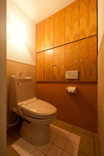 a bathroom with a toilet and wooden cabinets at Hotel Sun Garden Matsuyama in Matsuyama