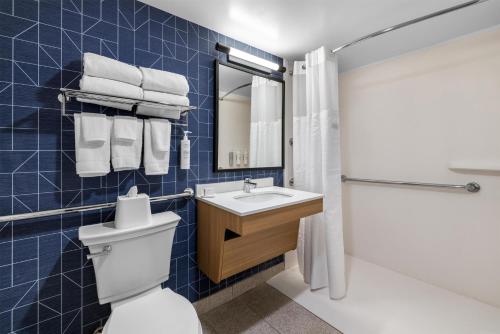 a blue tiled bathroom with a toilet and a sink at Spark By Hilton Hamburg in Hamburg