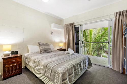 a bedroom with a bed and a large window at Mango Tree Holiday Apartments in Port Douglas