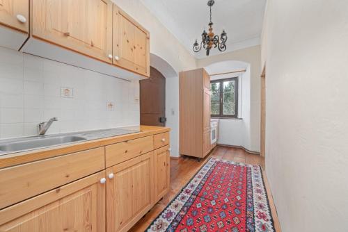 a kitchen with wooden cabinets and a rug on the floor at Schloss Berg Klösterle in Zedlitzdorf