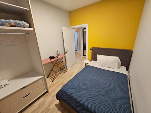 a small room with a bed and a yellow wall at central apart in Tirana