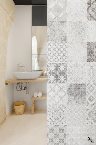 a bathroom with a sink and a tile wall at Hydria Rooms in Matera