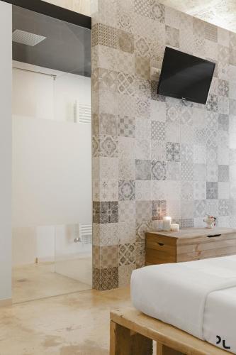 a bedroom with a bed and a tv on a wall at Hydria Rooms in Matera