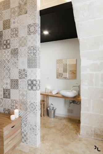 a bathroom with a sink and a stone wall at Hydria Rooms in Matera