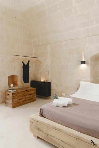 a bedroom with a bed in a room with a stone wall at Hydria Rooms in Matera