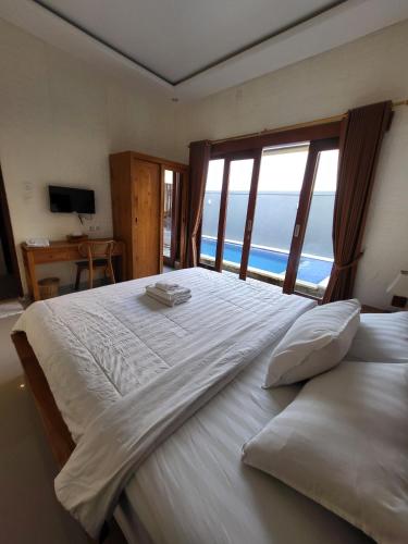 a bedroom with a large white bed with a large window at Pondok Ashanara Sading in Sempidi