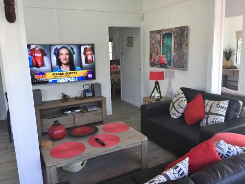 a living room with a couch and a tv at Sunrise on the Esplanade in Yeppoon