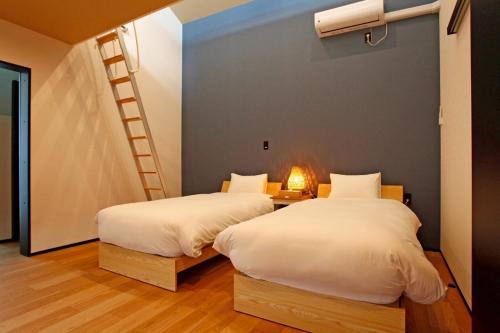 two beds in a room with a ladder on the wall at Nord SUR in Ichinomiya