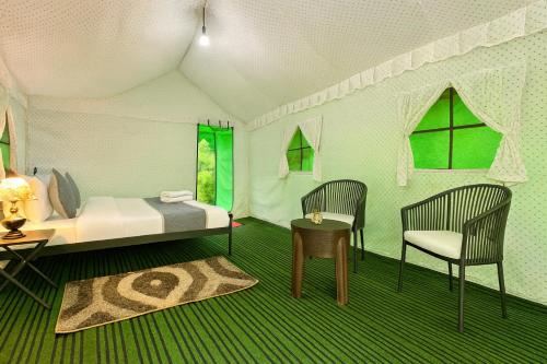 a room with a bed and two chairs and a table at The Himalayan Swiss Cottage with Bonfire, Manali - A Riverside Retreat in Manāli