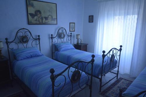 two beds in a bedroom with blue walls at Borgo della Rocca in Montemurlo