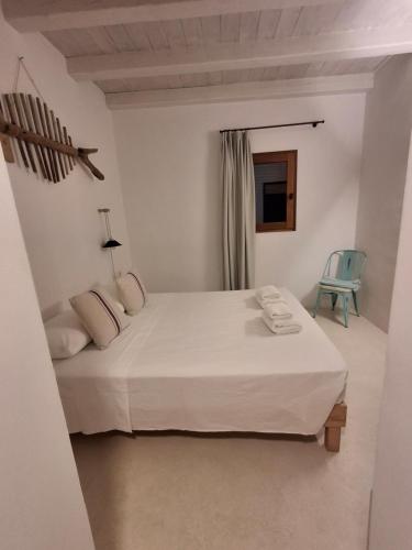 a white bedroom with a bed and a blue chair at A beautiful villa close to the beach in Playa Migjorn