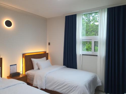 a hotel room with two beds and a window at Y2 Stay Hotel in Sokcho