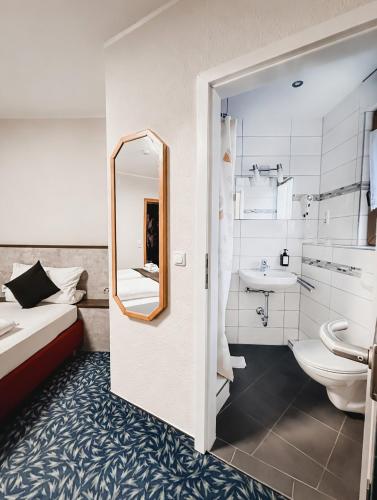 a bathroom with a bed and a sink and a mirror at Hotel Kühns Mühle in Oestrich-Winkel