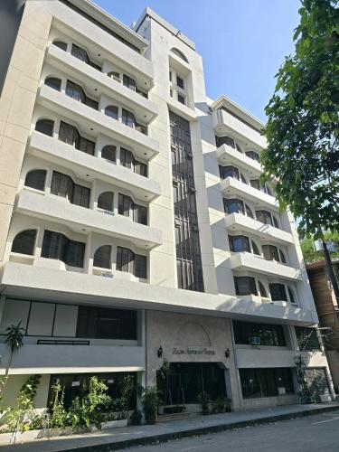 a large white apartment building on a street at Ralph Anthony Suites Hotel in Manila