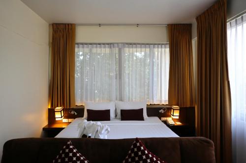 a bedroom with a large bed and a large window at Hotel M Chiang Mai in Chiang Mai