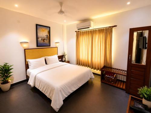 a bedroom with a large white bed and a television at The Regatta Landing in Alleppey