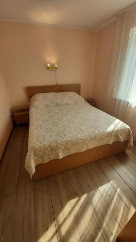 a bedroom with a bed and a wooden floor at Apartamentai Nidoje pas Virginą in Nida