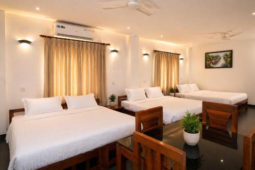 a hotel room with two beds with white sheets at The Regatta Landing in Alleppey