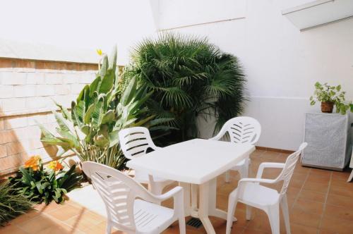 une table et des chaises blanches sur une terrasse ornée de plantes dans l'établissement Apartaments Bonaventura 24, à Sitges
