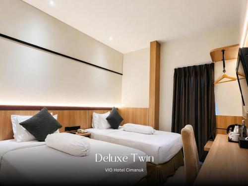 a hotel room with two beds and a desk at Vio Hotel Cimanuk Bandung in Bandung