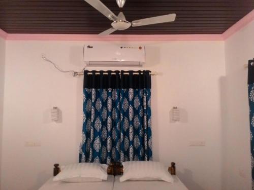 a bedroom with a ceiling fan and a blue curtain at Marari Babu Homestay in Mararikulam