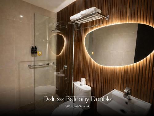 a bathroom with a mirror and a toilet and a sink at Vio Hotel Cimanuk Bandung in Bandung