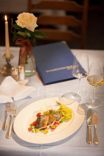 a plate of food on a table with wine glasses at Parkhotel Tristachersee in Lienz