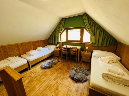 a attic room with three beds and a table at Hotel Bystrina in Belá