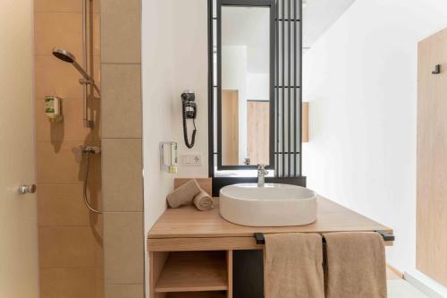 ein Badezimmer mit Waschbecken und Spiegel in der Unterkunft eee Hotel Laakirchen in Laakirchen