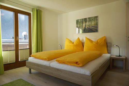 ein Schlafzimmer mit einem Bett mit gelben Kissen und einem Fenster in der Unterkunft Appart Rosa in Pfunds